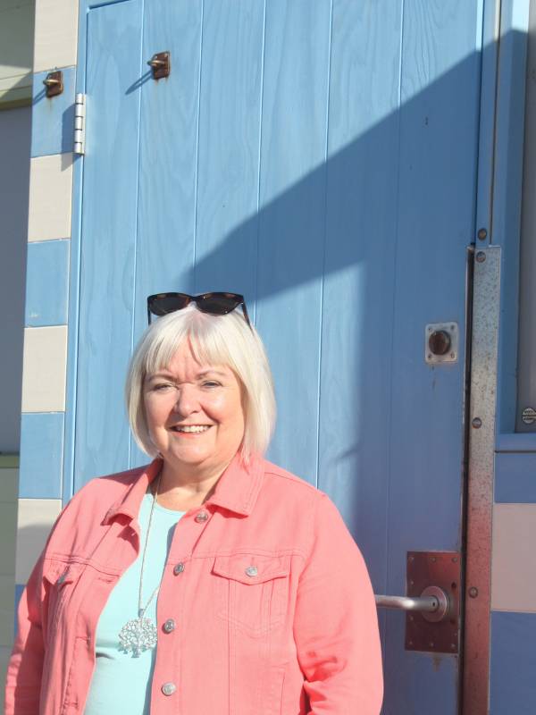 Suzanne Mountain Business Coach in front of Seaford Beach hut in the bright sunshine