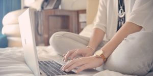 woman working on monthly action plan on her laptop in bed